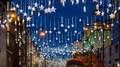 Festive Christmas decorations in the streets of London with red bus traffic during night time