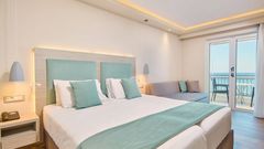 Helles, modern eingerichtetes Doppelzimmer mit eleganter Farbkombination aus Weiß und Mint sowie direktem Zugang zum Balkon mit traumhaftem Meerblick.