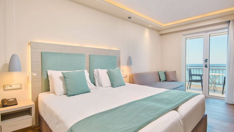 Helles, modern eingerichtetes Doppelzimmer mit eleganter Farbkombination aus Weiß und Mint sowie direktem Zugang zum Balkon mit traumhaftem Meerblick.