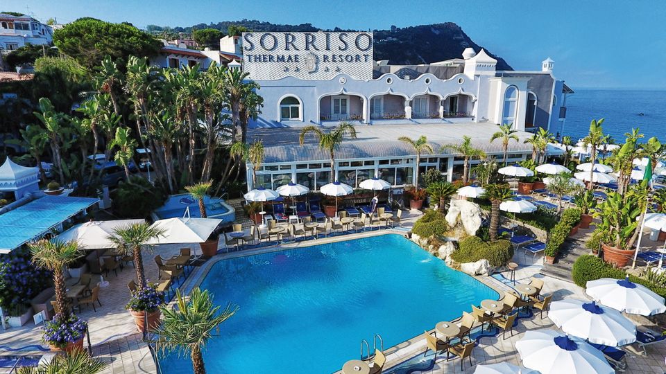 Blick auf Hotel Sorriso Thermae mit Pool und Palmen in Italien, Ischia