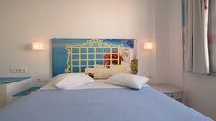 Helles Zimmer mit Doppelbett, dekorativem Fotokopfteil mit Meerblick-Motiv und mediterraner Atmosphäre – ideal für entspannte Urlaubstage.