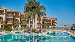 Weitläufige Poolanlage mit eleganter Brücke, umgeben von tropischer Bepflanzung und blühenden Bougainvillea – ideal für entspannte Stunden unter südlicher Sonne.