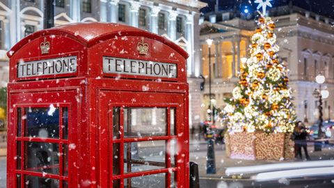 Rote Telefonzelle in London vor einem beleuchtetem Weihnachtsbau