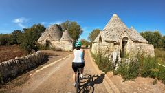 Radfahrerin bei Trulli-Häusern in Apulien