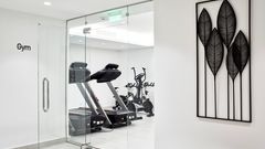 Modern ausgestatteter Fitnessraum im Costa Grand Resort & Spa mit Laufbändern und Ergometern – stilvolles, lichtdurchflutetes Ambiente mit Glaswänden und minimalistischer Dekoration.